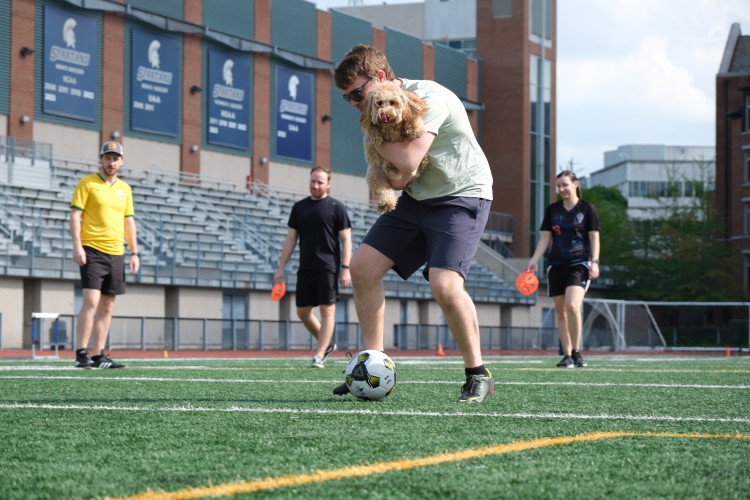 Internal Medicine resident dribbling soccer ball while carrying a dog