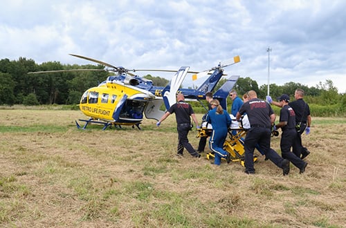 Trainees walking cot to medical helicopter