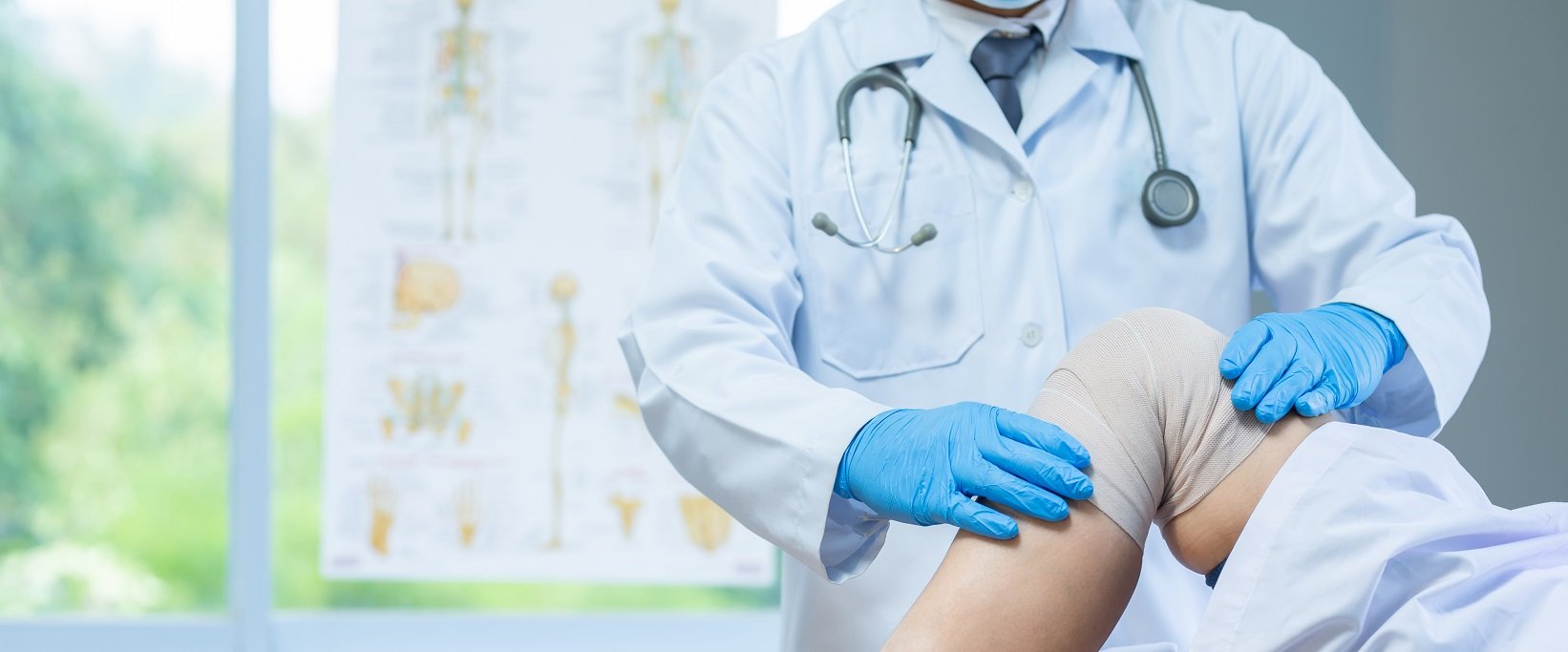 Resident examining patient's knee in exam room